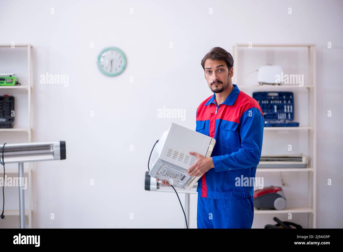 Young repairman repairing oven at workshop Stock Photo