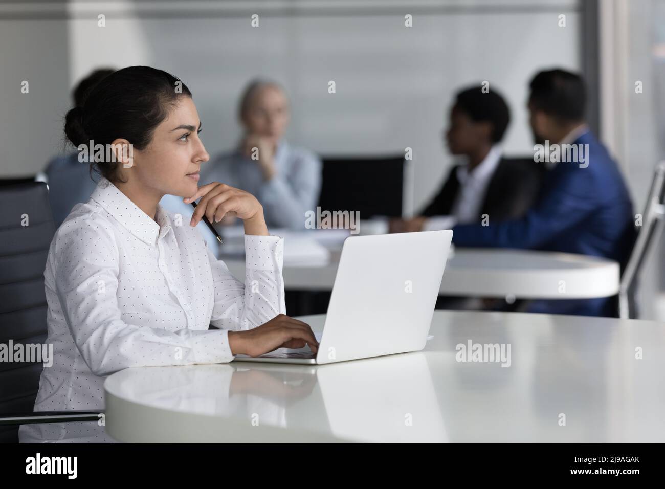 Indian employee thinking over task sit at desk with laptop Stock Photo