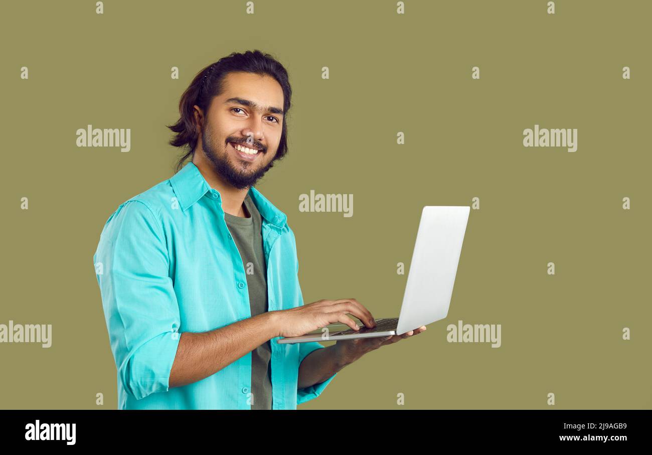 Happy young Indian student or IT specialist using his laptop computer and smiling Stock Photo