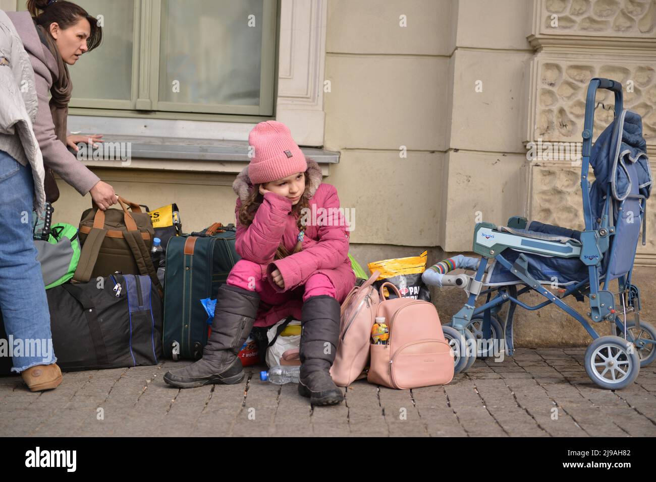 Ukrainian girl is seen sitting outside the train station. Refugees from Ukraine arrive at the train station in Przemysl, Poland, on the 20th day of the Russian invasion of their country. Stock Photo