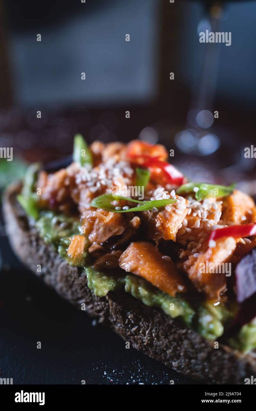 person eats fresh sandwich with avocado, red salmon fried fish, seaweed, pepper Stock Photo