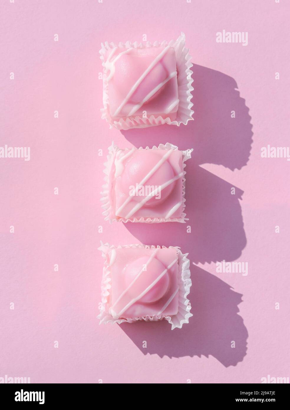 Pink fondant icing on sponge cakes set on a pastel pink background. Stock Photo