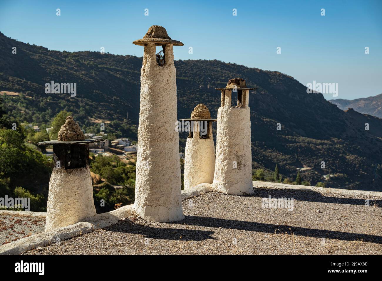 Typical chimneys on a rooftop in Capileira, with the Poqueira valley in the background, Las Alpujarras, Sierra Nevada National Park, Andalusia, Spain Stock Photo