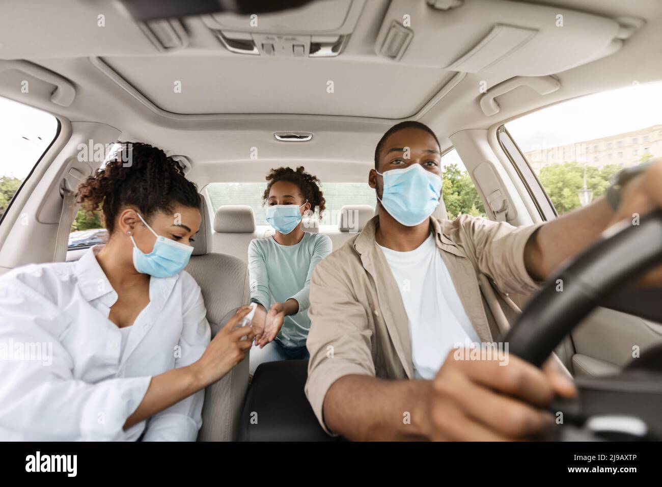 Black Family Of Three Using Sanitizer In Car, Disinfecting Hands Stock ...