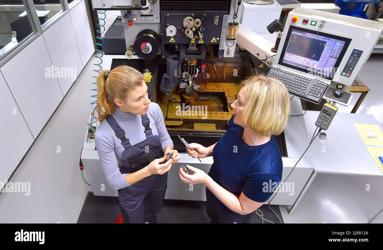 A female trainee receives technical tuition from her instructor. Both women work as computerized  numerical control engineers. Stock Photo