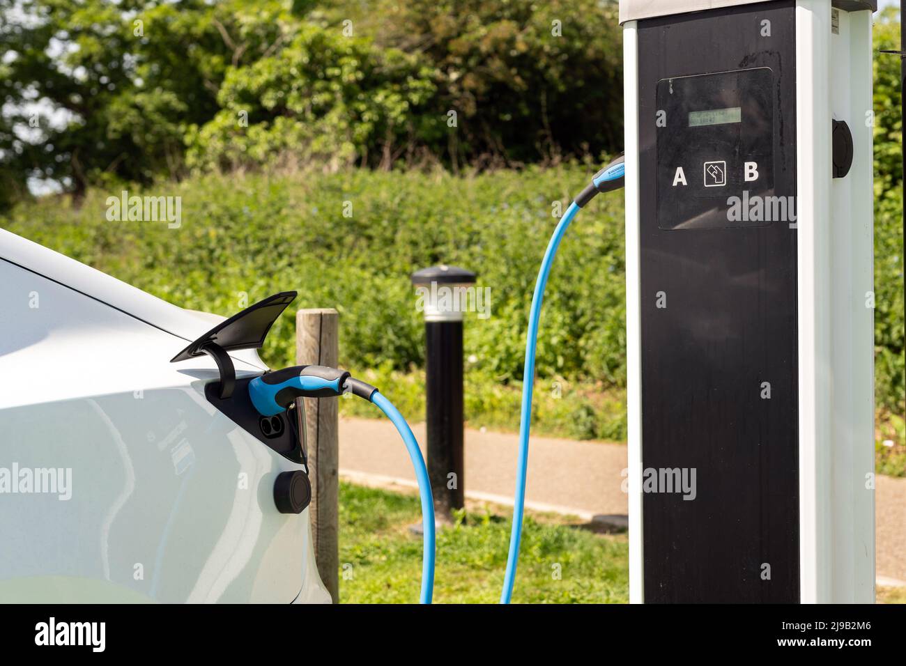 Electric car charging at plug-in charge station in a public car park in Suffolk, UK Stock Photo