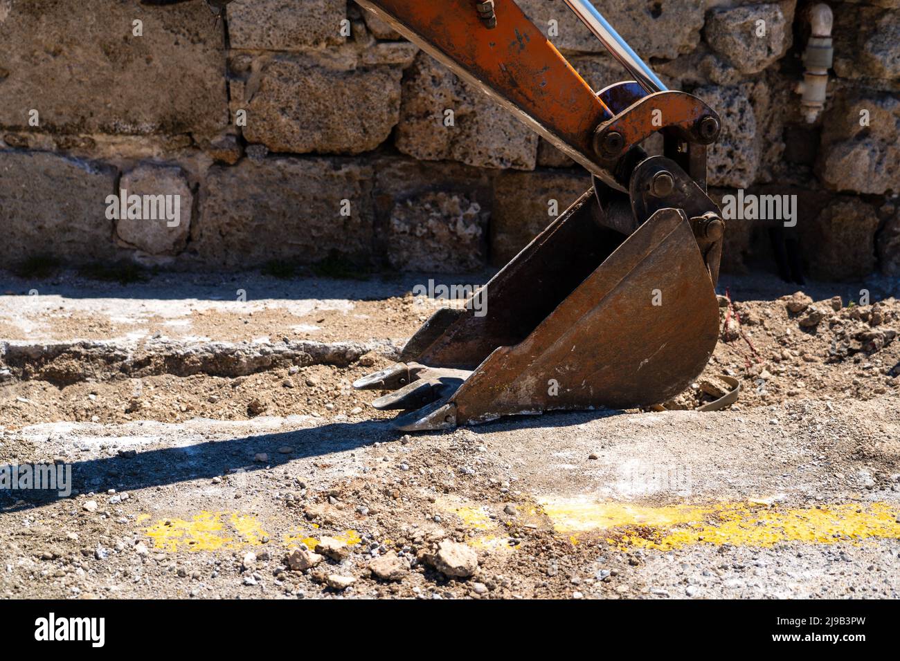 Excavators dipper or stick digging in a road to fix same pipeline. Stock Photo