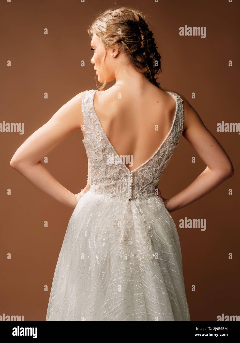 Luxury shiny lace wedding dress. Summer backless sleeveless bridal gown  with long skirt. Beautiful blonde lady bride posing in studio on brown  backgro Stock Photo - Alamy