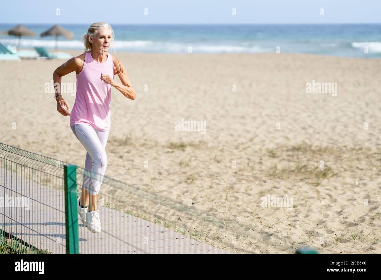Mature woman running along the beach hi-res stock photography and images -  Alamy