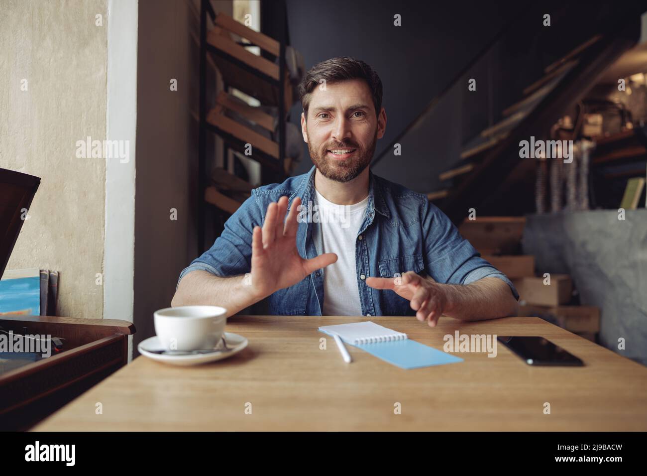 Portrait of Caucasian happy attractive male vlogger talking to camera. Vlog at coffee time. Blogger. Stock Photo