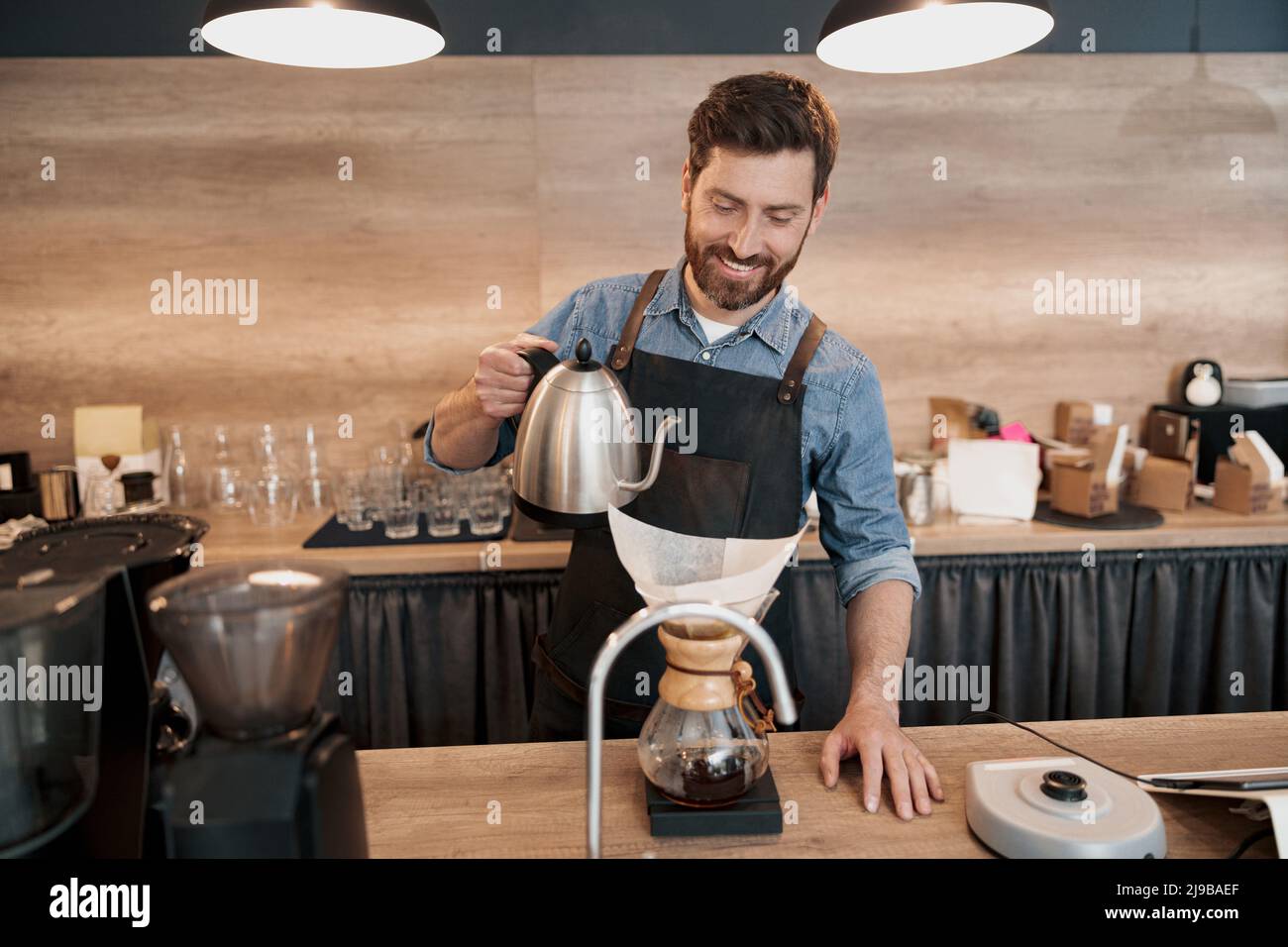Smiling Barista pouring water to make coffee using manual drip brewer