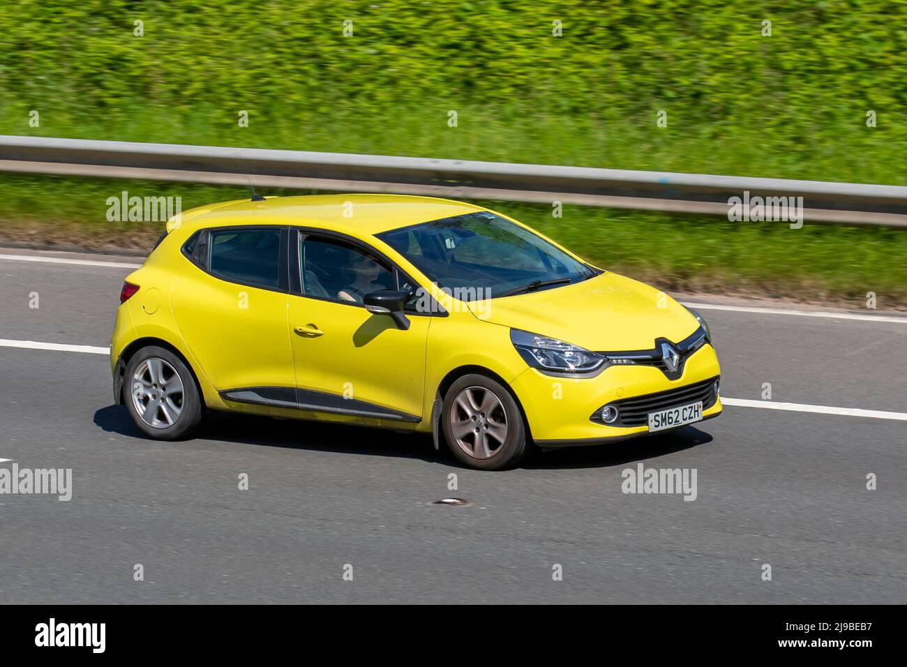 2013 yellow Renault Clio D-Que M-Nav Energy Tce Ss 899 cc petrol hatchback; driving on the M6 Motorway, Manchester, UK Stock Photo