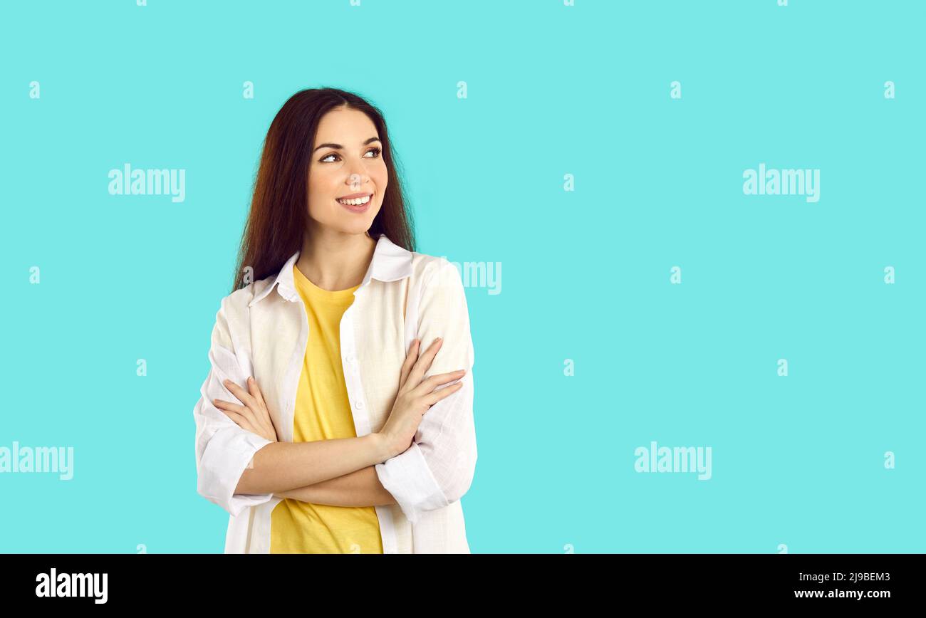 Happy young woman in casual wear looking sideways at turquoise copy space background Stock Photo