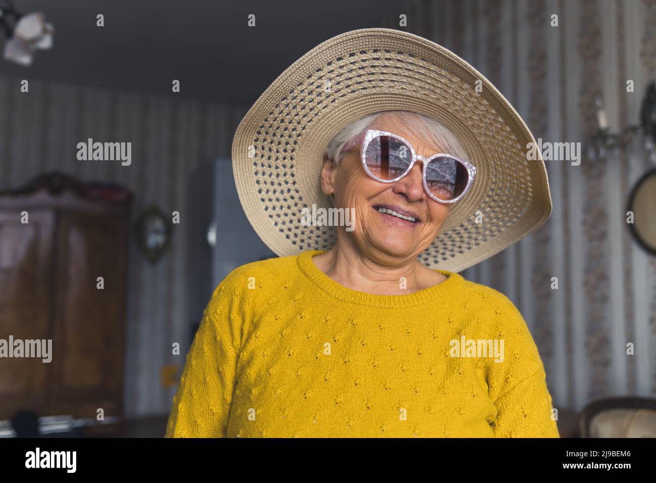 cute senior Caucasian woman with a hat and sunglasses in the living room medium closeup senior people support concept. High quality photo Stock Photo