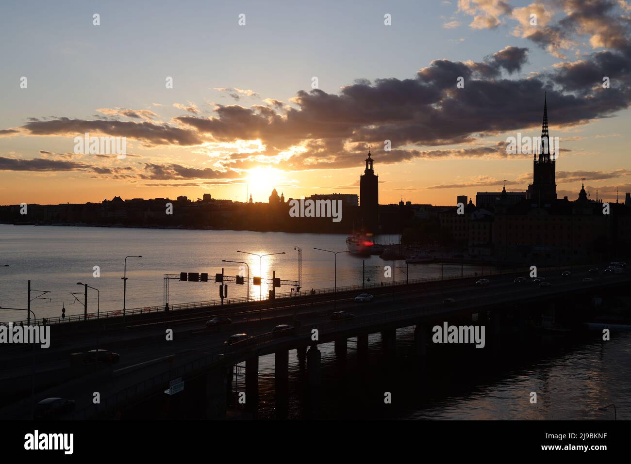 View over the city of Stockholm, capital of Sweden,seen over the water from Slussen during the Golden Hour. Clouds in the sky; sun reflects in water Stock Photo