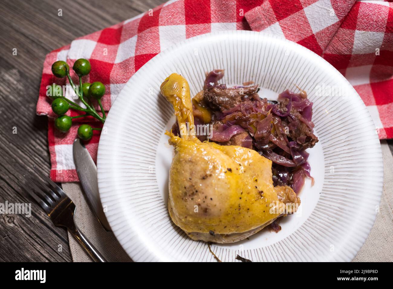 Fried chicken thigh with braised red cabbage. Ugly food photo. View from above. Checkered napkin. Stock Photo