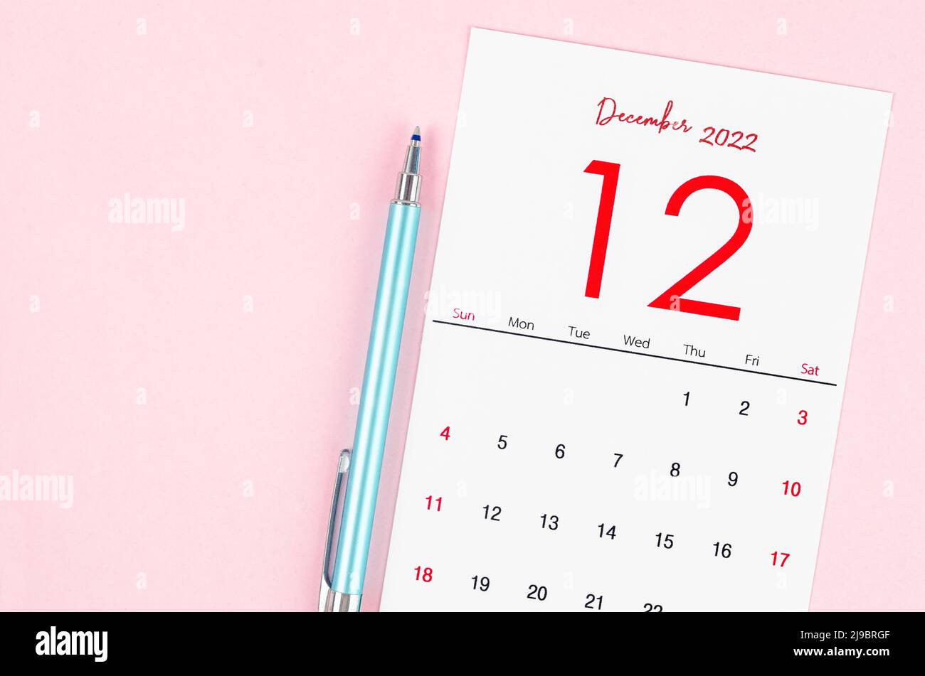 The December 2022 calendar with pen on pink background. Stock Photo