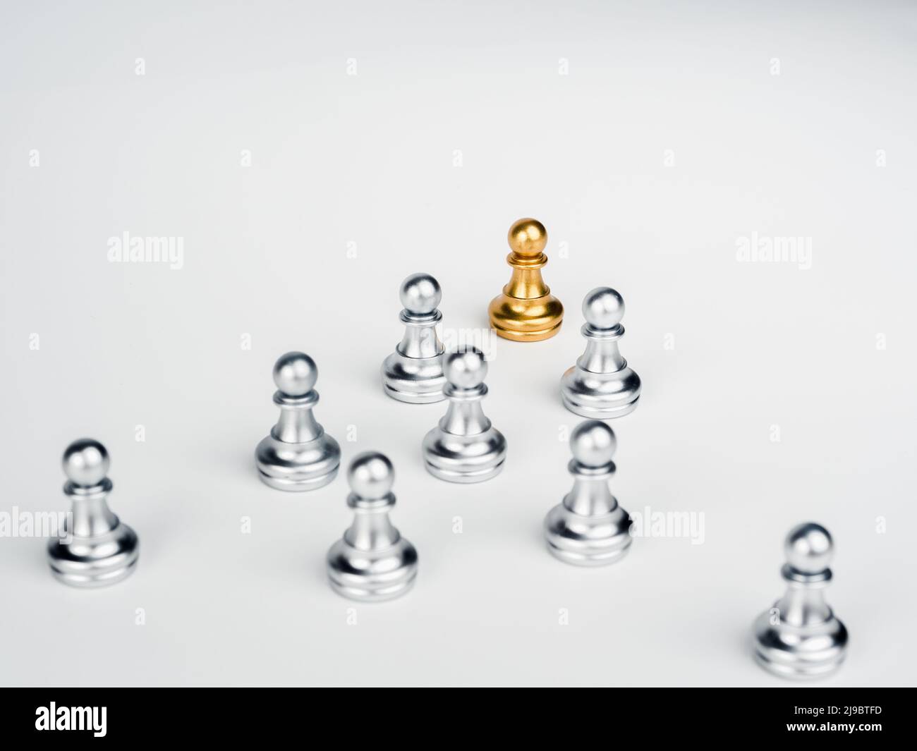 The golden pawn chess piece, leading in front of the group of silver