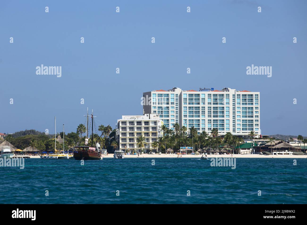 PALM BEACH, ARUBA - OCTOBER 17, 2021: View from the sea of Hotel Radisson Blu, in the front buildings of Holiday Inn Resort and tour boats on Aruba Stock Photo