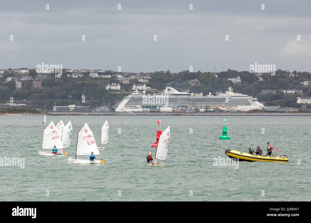 Crosshaven, Cork, Ireland. 22nd May, 2022. Against a background of the cruise ship Jewel of the Seas some of the competitors taking part in the IODAI Optimist Munster Championship  that was held in Crosshaven, Co. Cork, Ireland over the weekend. - Credit; David Creedon / Alamy Live News Stock Photo