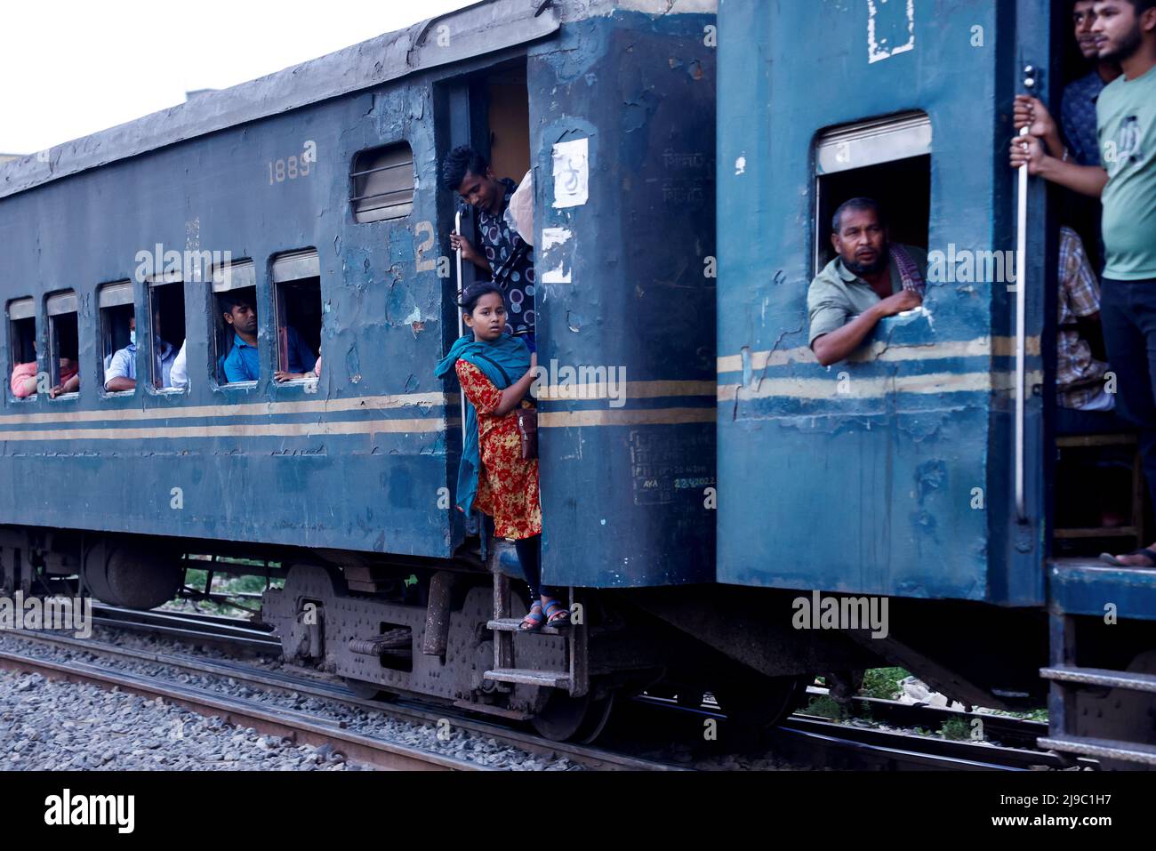 A girl stands by the door of a moving train in Dhaka, Bangladesh, May 22, 2022. REUTERS/Mohammad Ponir Hossain Stock Photo