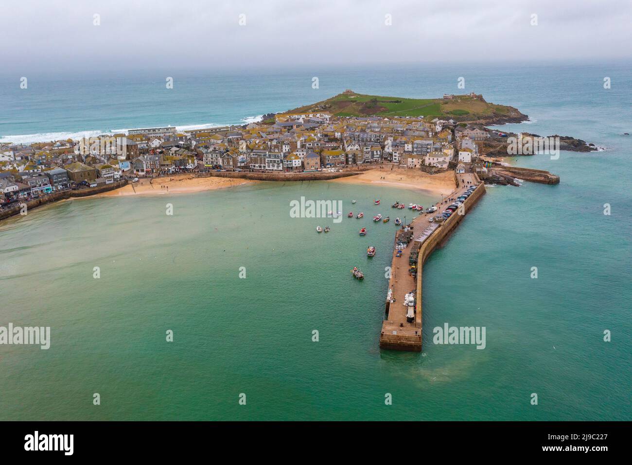 Boats bob in the harbour of this traditional Cornwall seaside town with a lighthouse pier. Stock Photo
