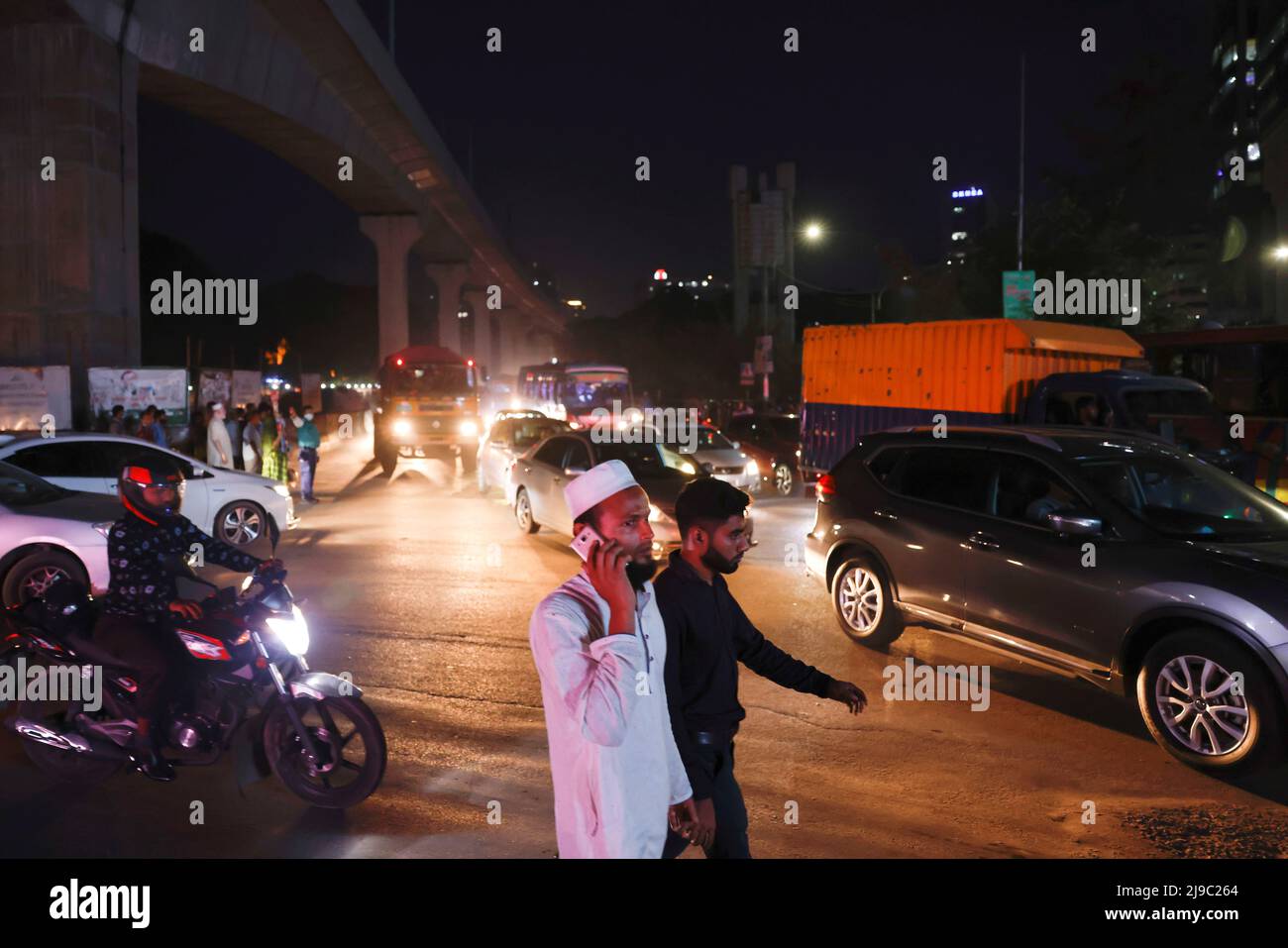 A man talks on his phone while crossing a road at night, in Dhaka, Bangladesh, May 22, 2022. REUTERS/Mohammad Ponir Hossain Stock Photo