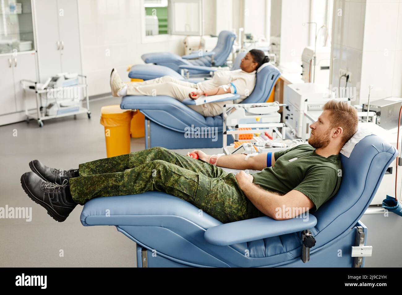 Group of blood donors in row laying on med chairs in donation center