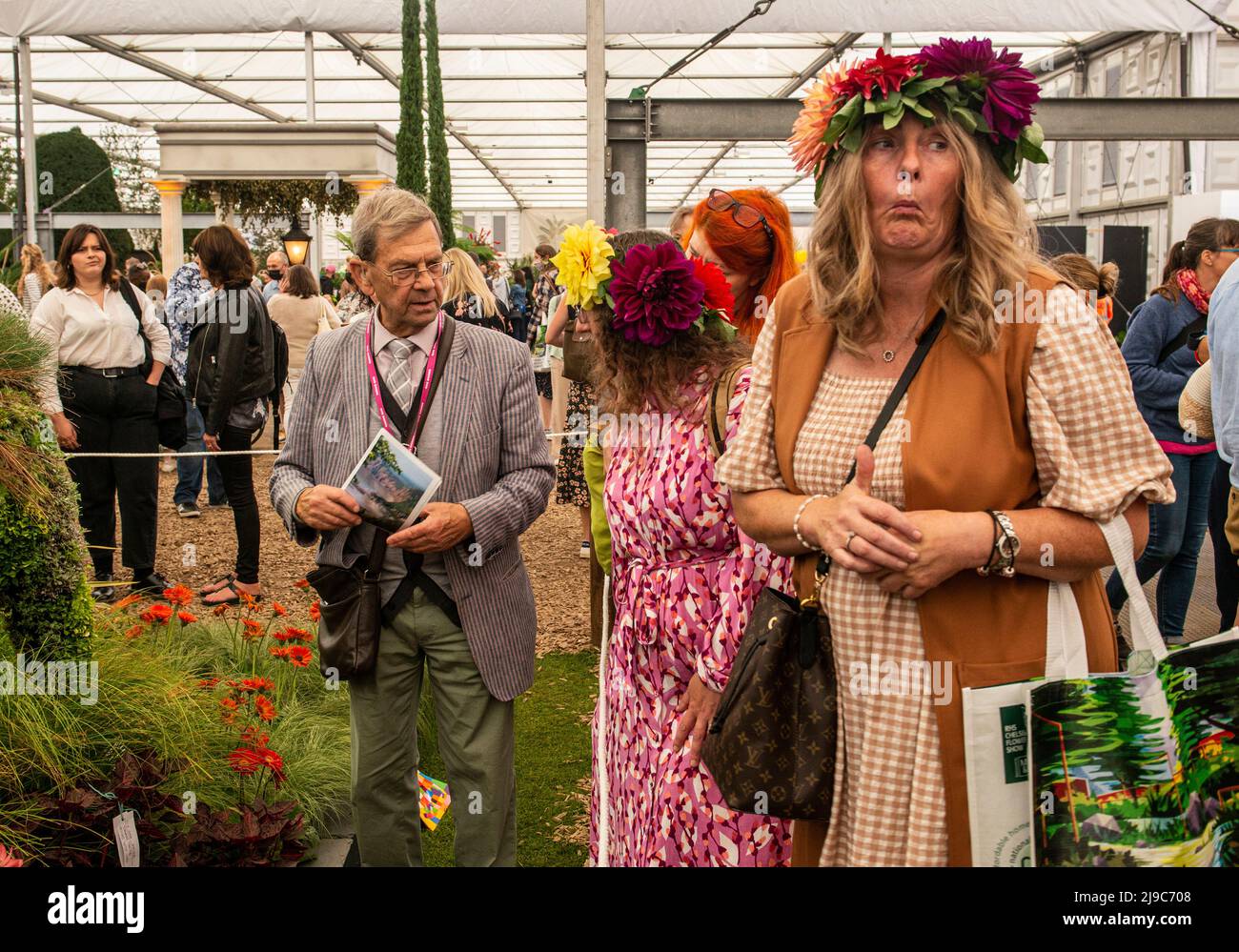A woman wearing a hat made of flowers pulls a funny face on the last day of the RHS Chelsea Flower Show. Stock Photo
