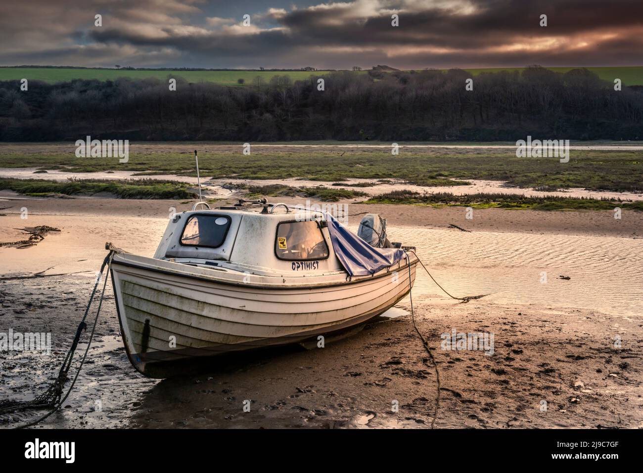 A small motor boat moored on the muddy foreshore of the Gannel River in Newquay in Cornwall. Stock Photo