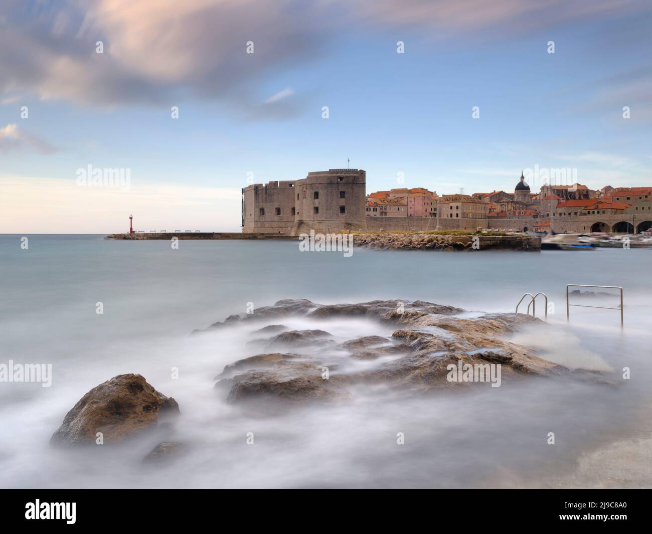 Waves washing over rocks in front of Dubrovnik Old Harbour. Stock Photo