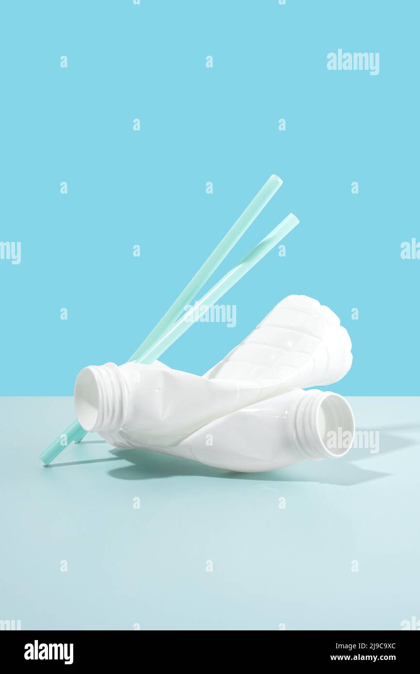 Negative impact on nature. Plastic bottles, straws on a minimalistic blue background. Soil pollution. The idea of plastic pollution. Concept Stock Photo