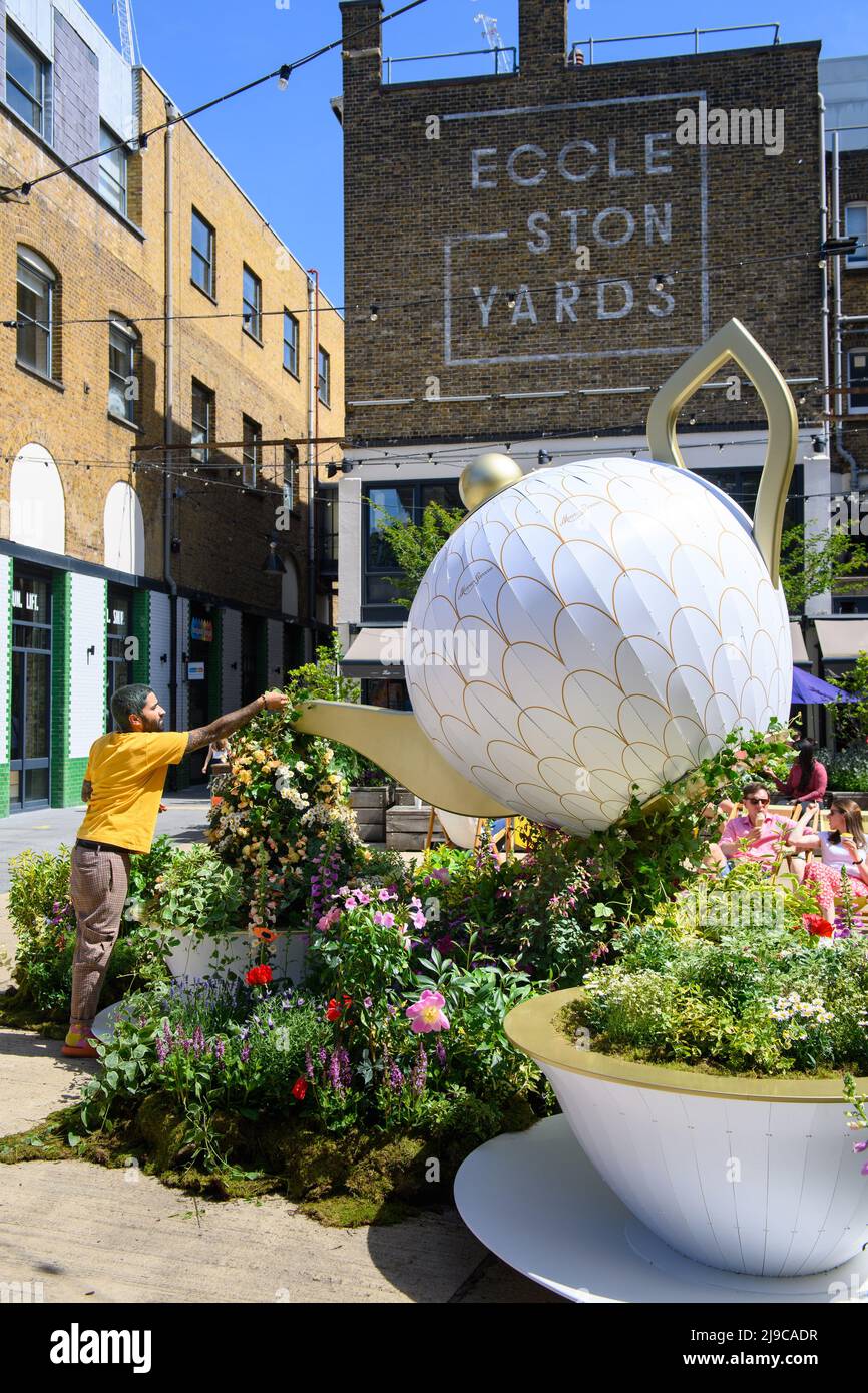 EDITORIAL USE ONLY Florist Ramin Kourani from Moyses Stevens puts the finishing touches to a floral installation featuring a pouring teapot titled Tea Garden in Eccleston Yards in London, which has been designed for the Belgravia in Bloom festival, running from May 23-29, London. Picture date: Monday May 23, 2022. Stock Photo