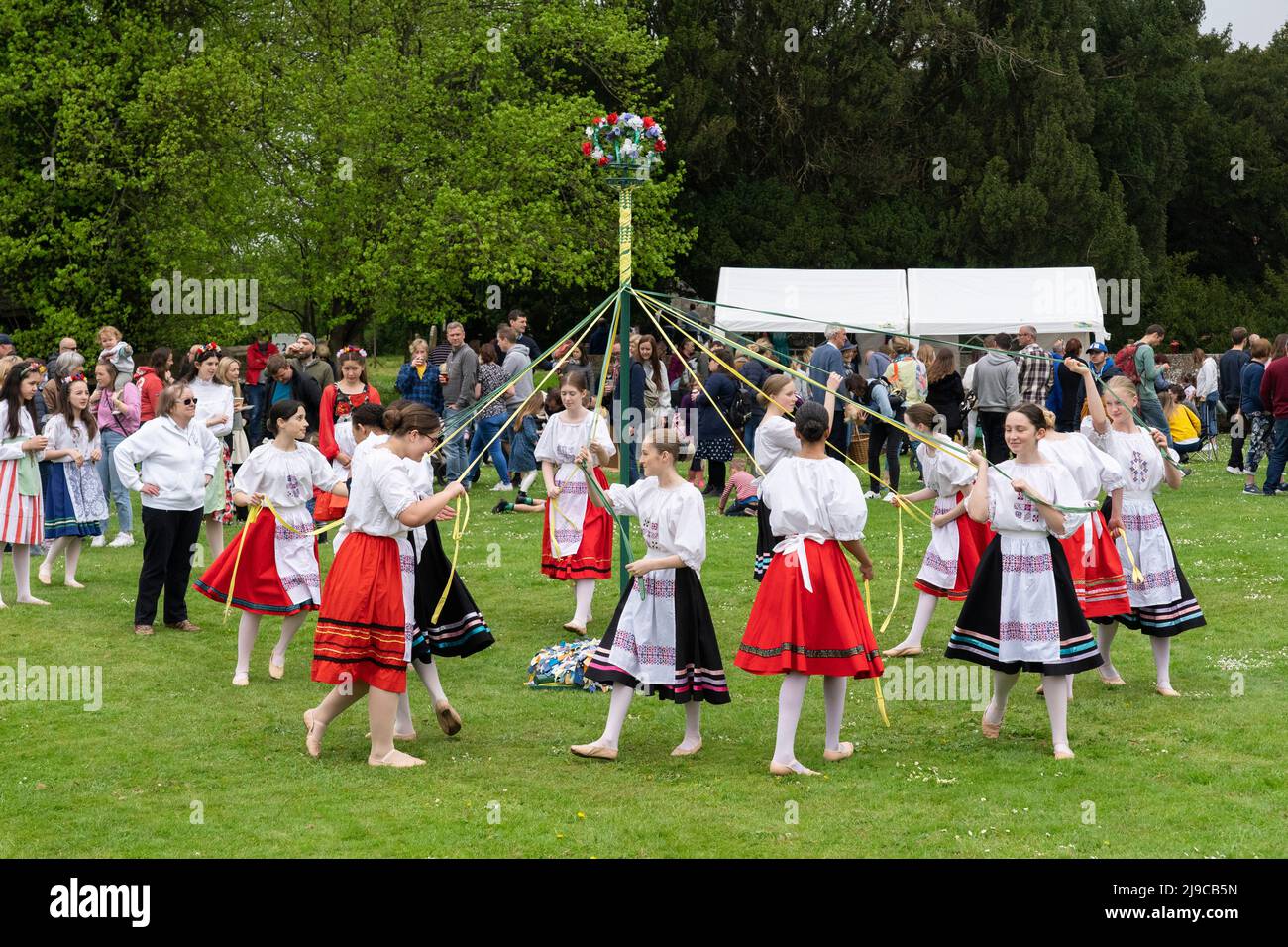 Children dancing around the Maypole on the village green at the Hurstbourne Priors May Fair on May 2nd 2022, Hampshire, England Stock Photo