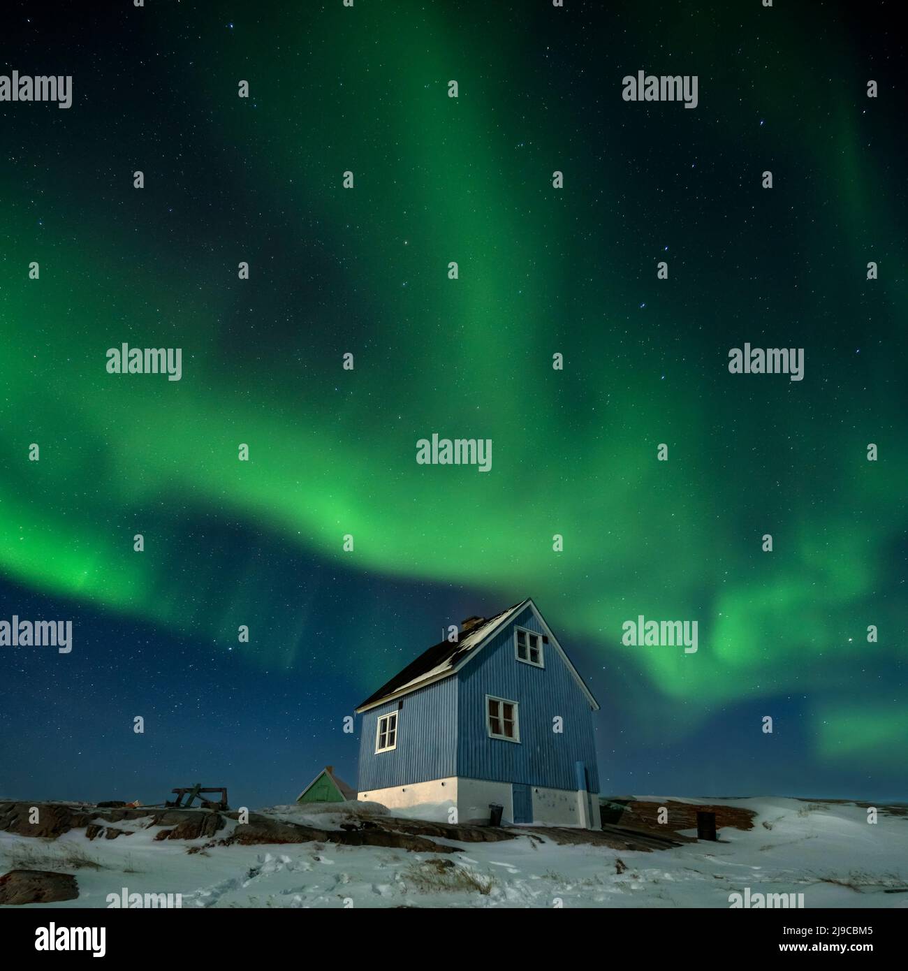 The northern lights over a blue house in Oqaatsut village in west Greenland. Stock Photo