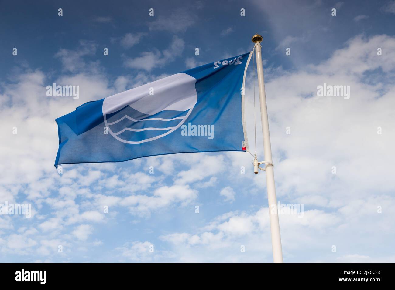 Prestigious Blue Flag flying on Mundesley Beach in North Nofolk, UK on a windy spring day Stock Photo