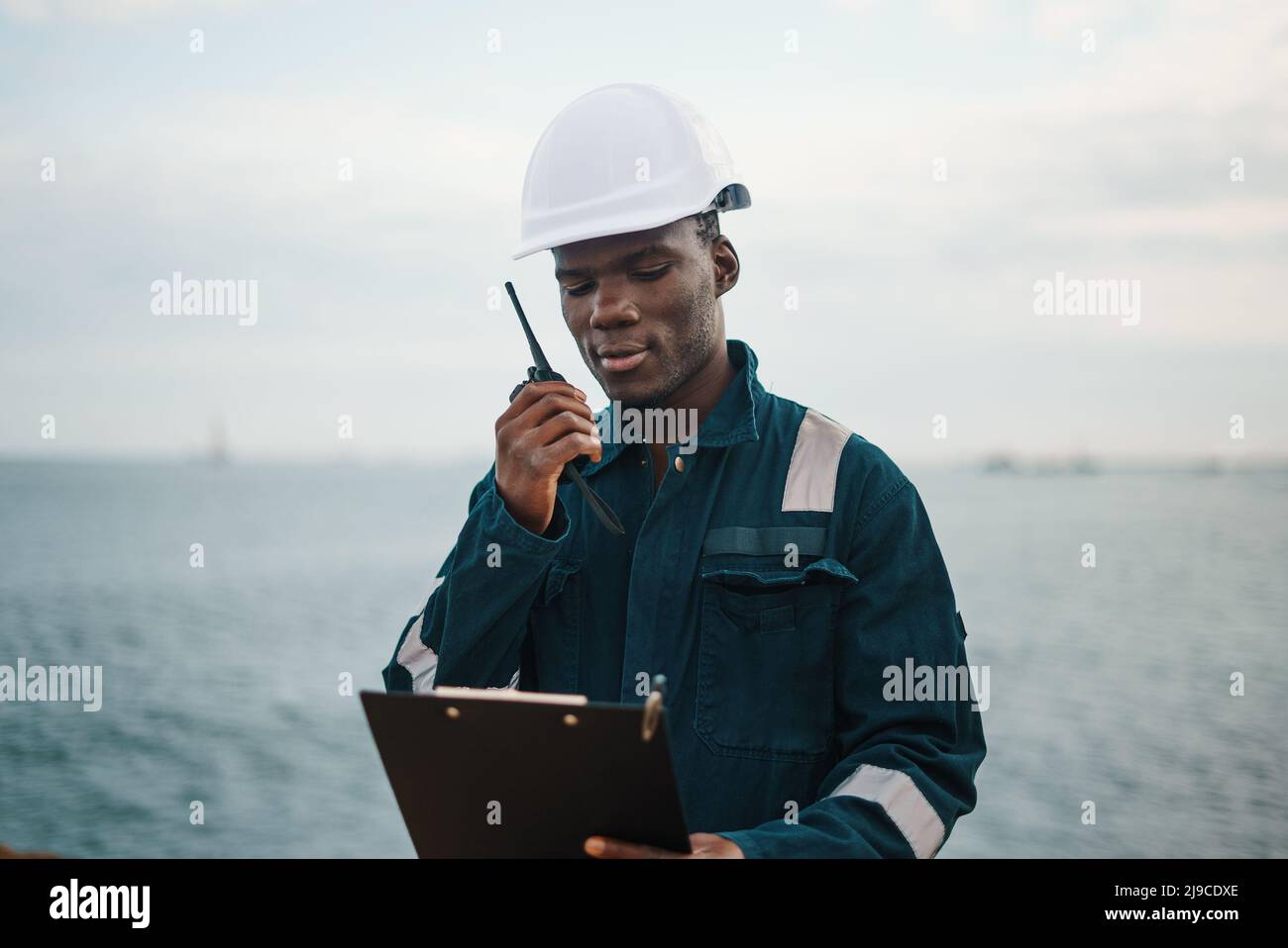 Black seaman reading document to colleague via radio Stock Photo