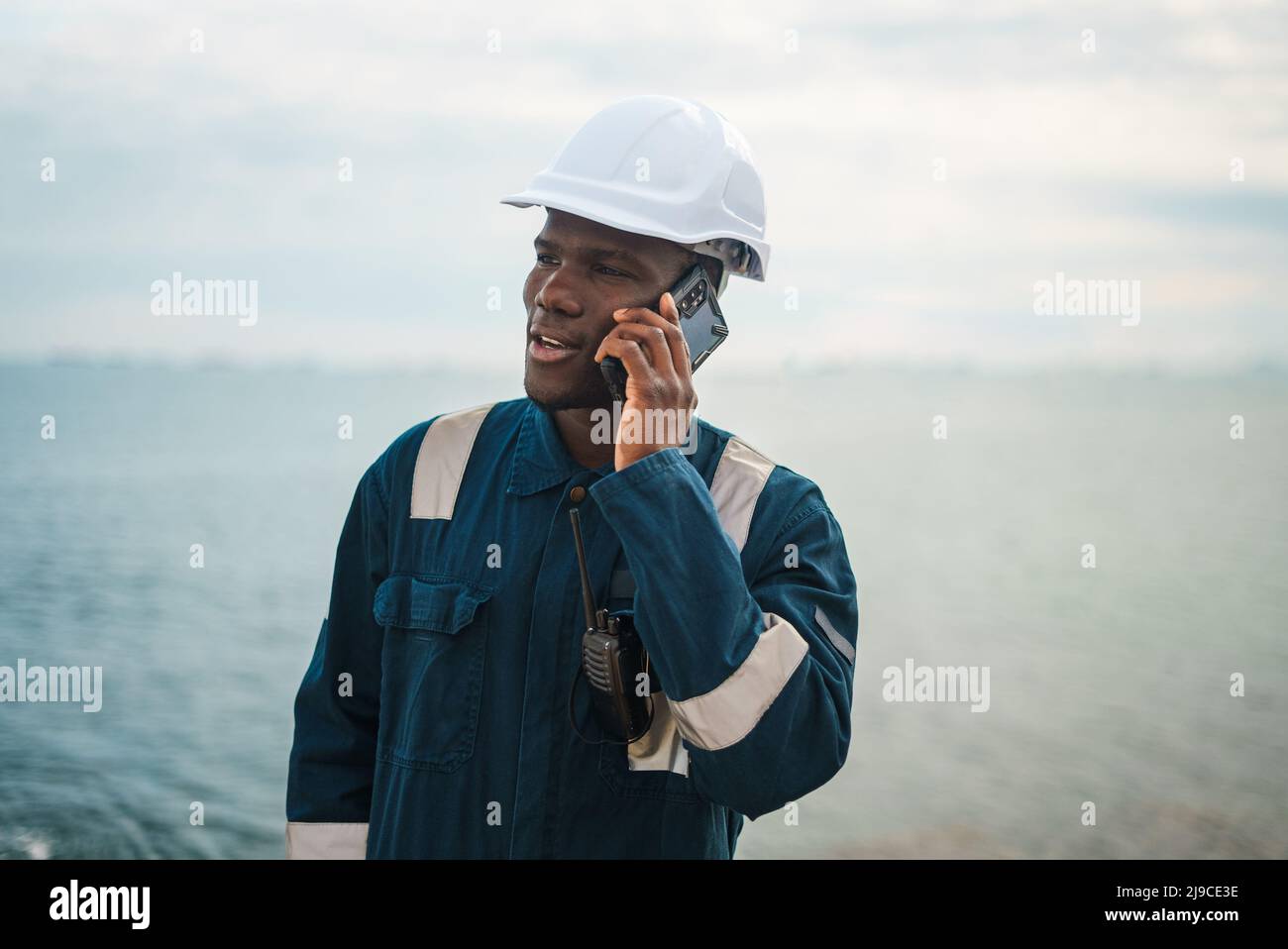 Black maritime worker speaking on mobile phone Stock Photo