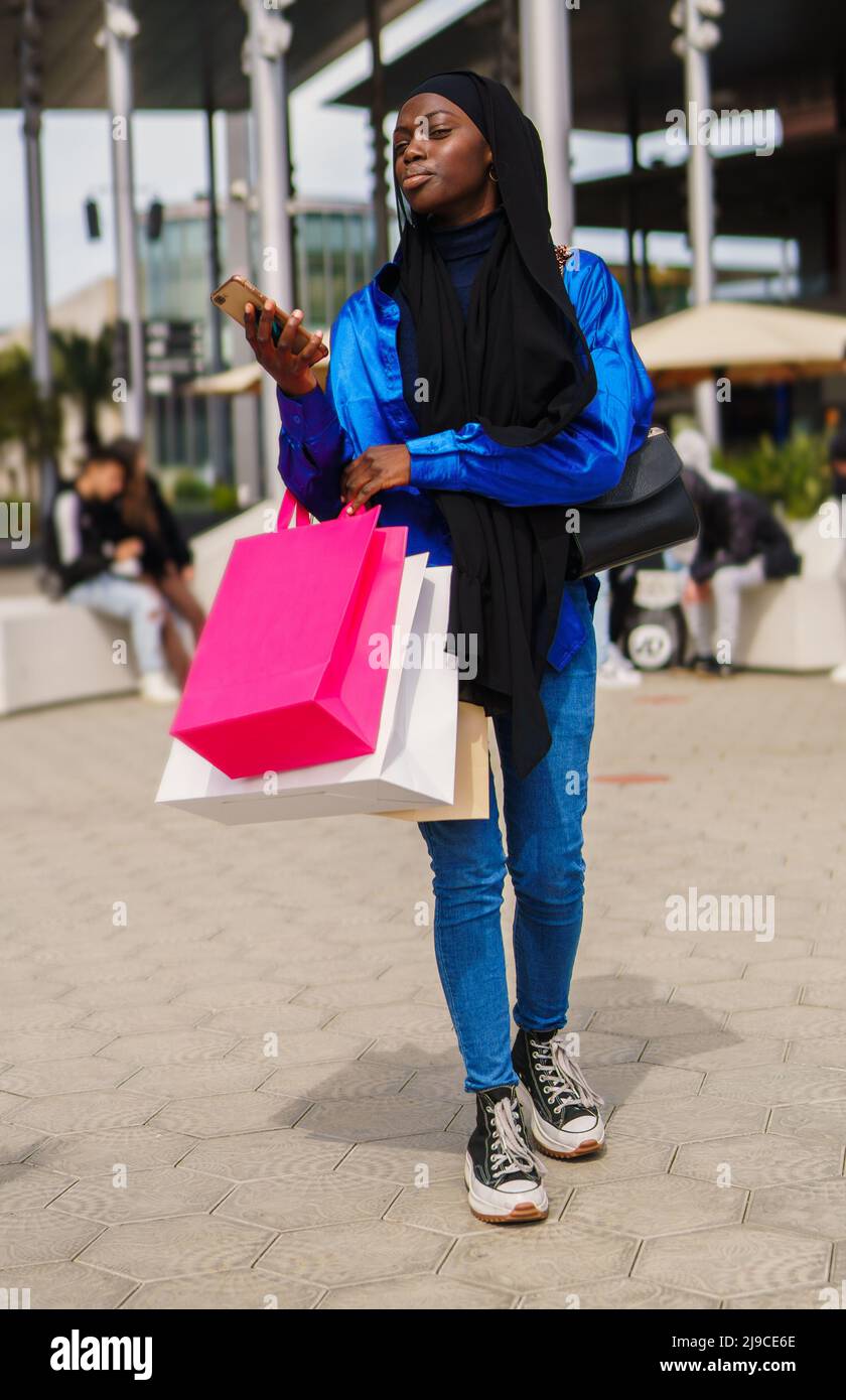 Black shopper with paper bags checking cellphone Stock Photo