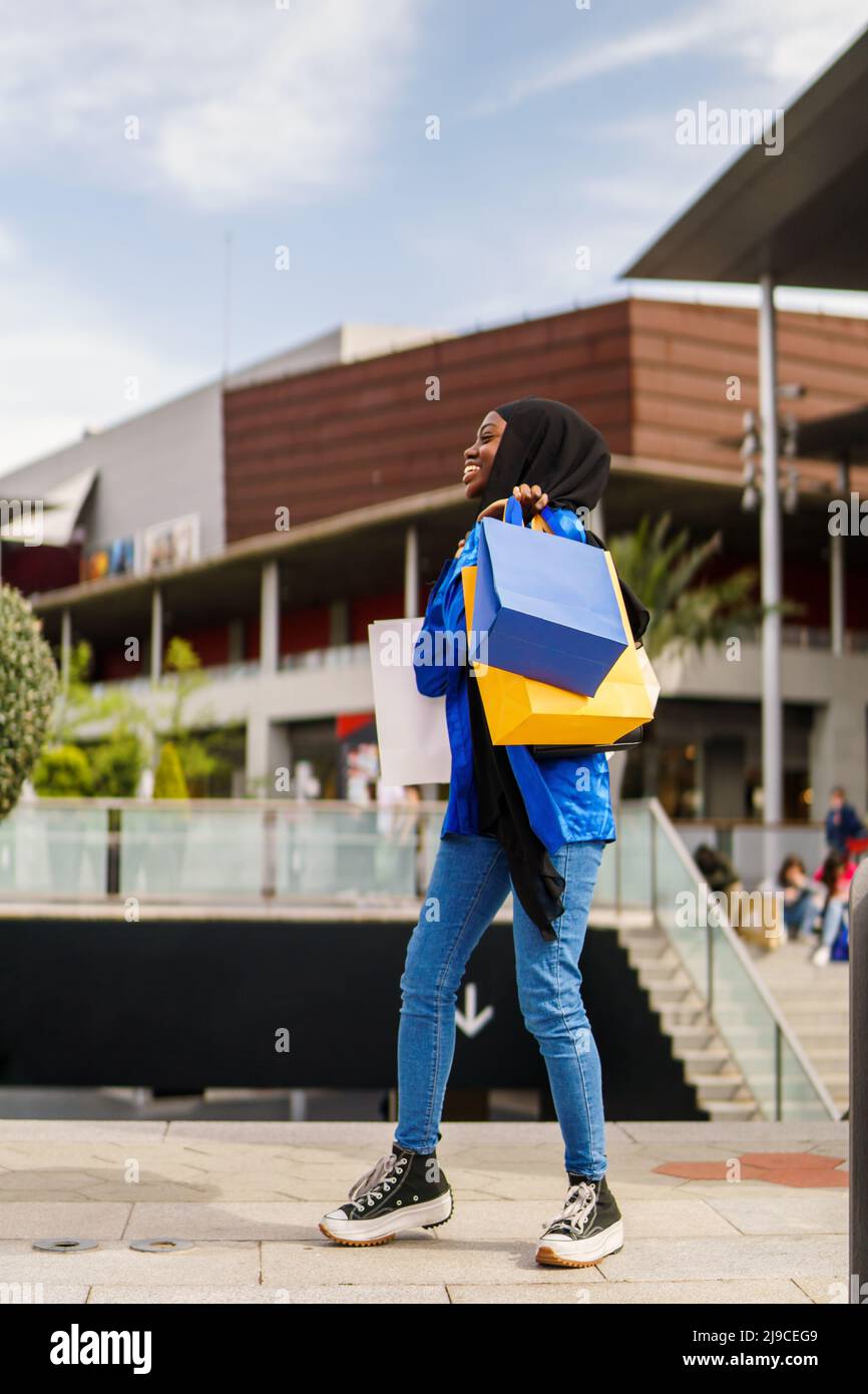 Trendy Muslim woman walking near shop Stock Photo