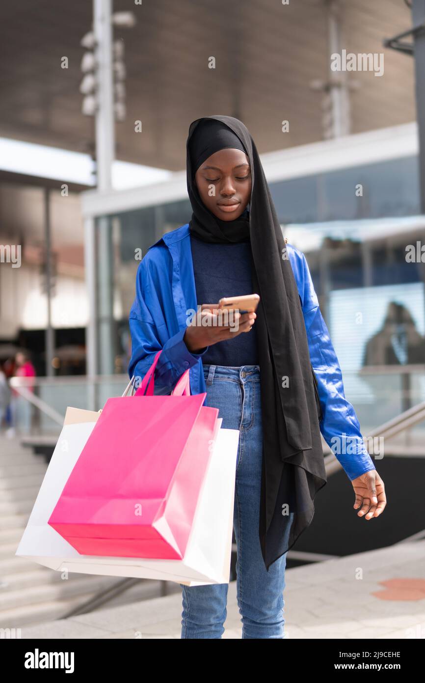 Muslim customer using cellphone near mall Stock Photo
