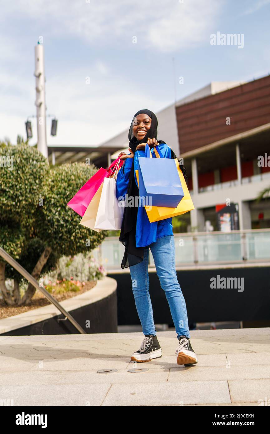 Gleeful Muslim customer with shopping bags on street Stock Photo