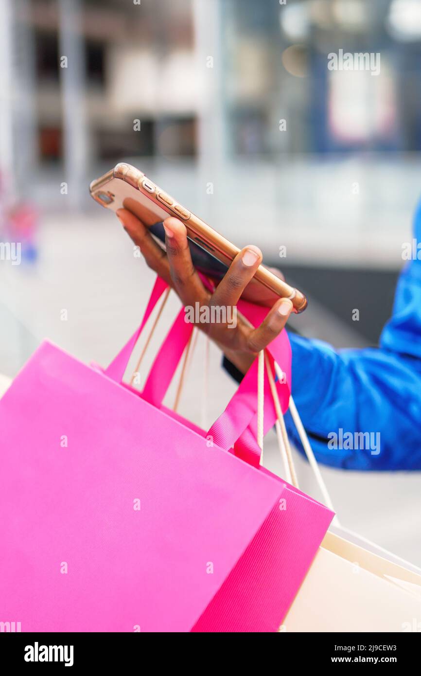 Crop shopaholic with paper bags using mobile phone Stock Photo