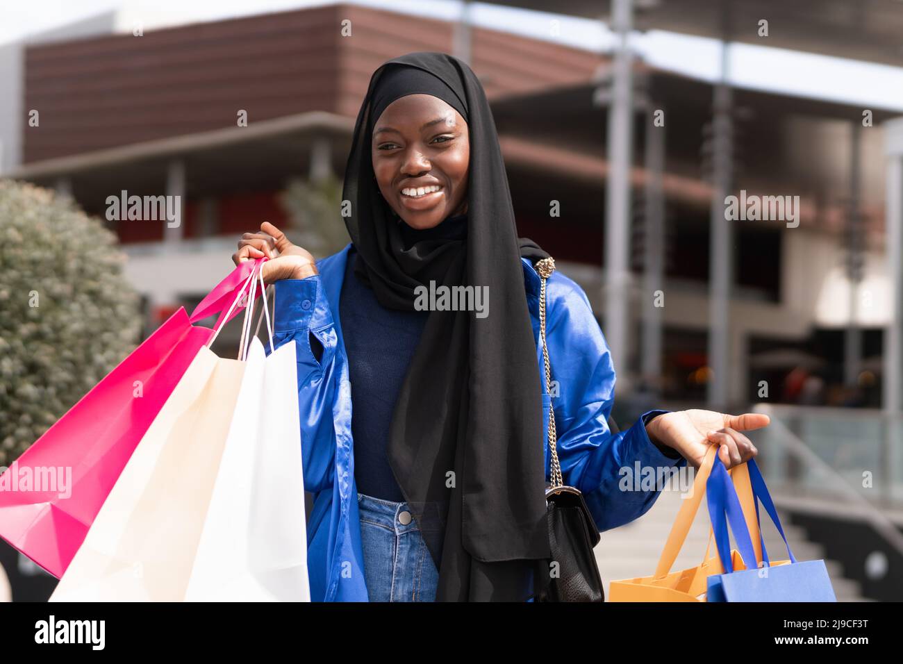 Happy black shopper in hijab with paper bags Stock Photo