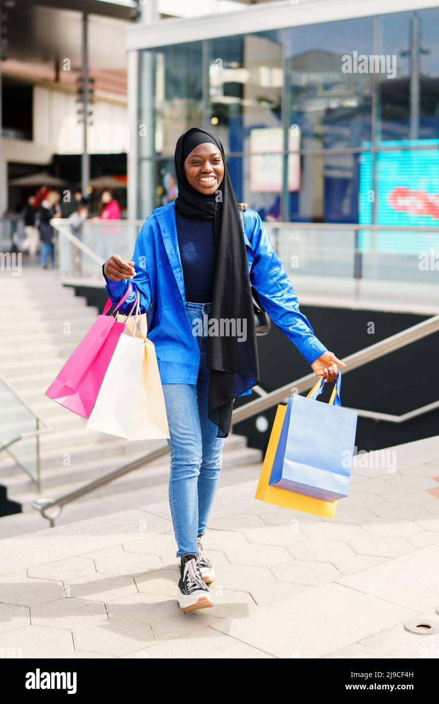 Cheerful Muslim woman leaving mall after shopping Stock Photo