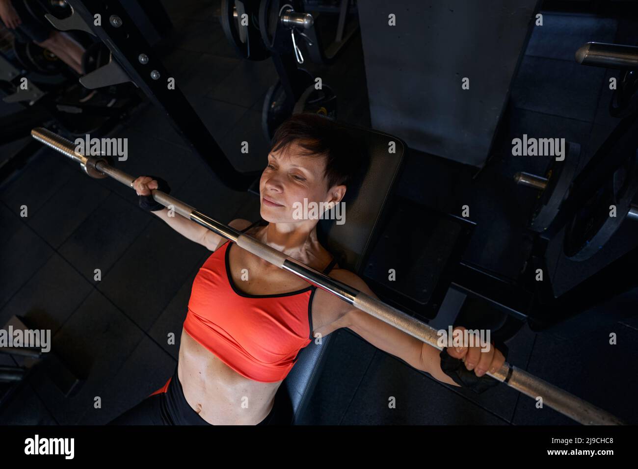 Focused female bodybuilder performing incline bench press Stock Photo