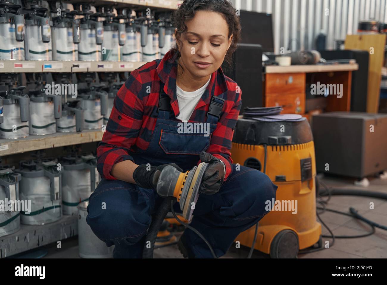Young auto mechanic preparing grinding machine for work Stock Photo