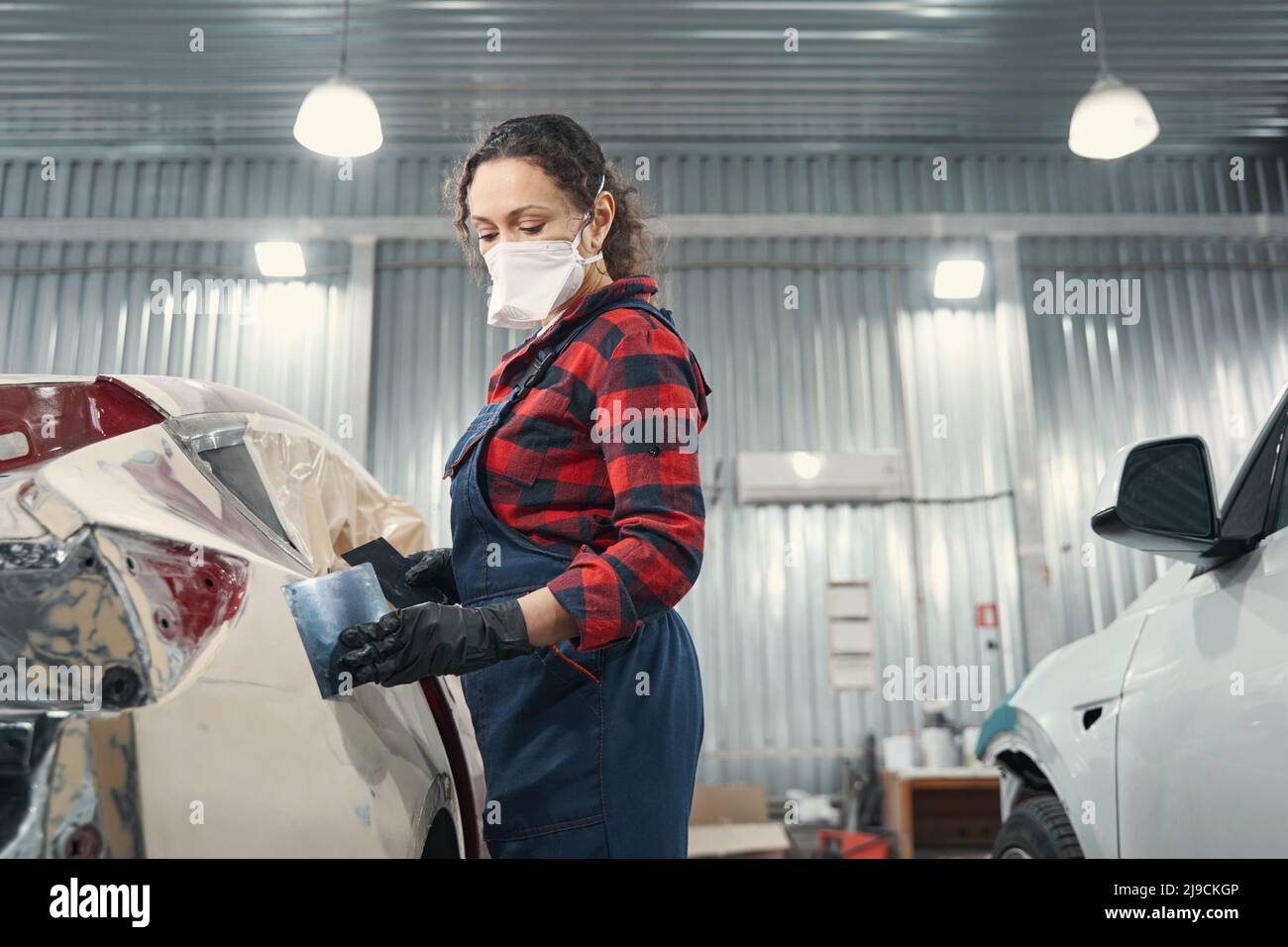 Attentive female master applying primer on car body Stock Photo Alamy