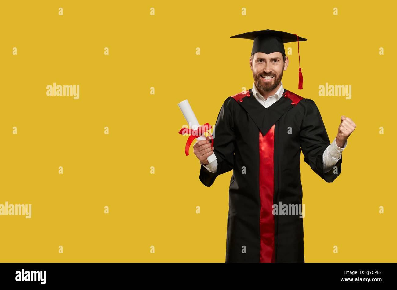 Front view of cheerful boy graduating from college, university. Male