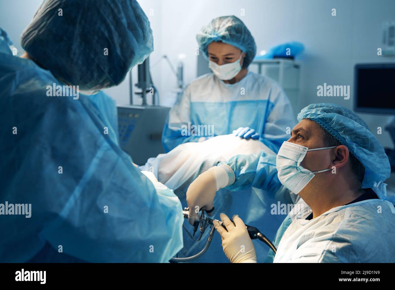 Surgeon looking at nurse while doing laparoscopic surgery Stock Photo